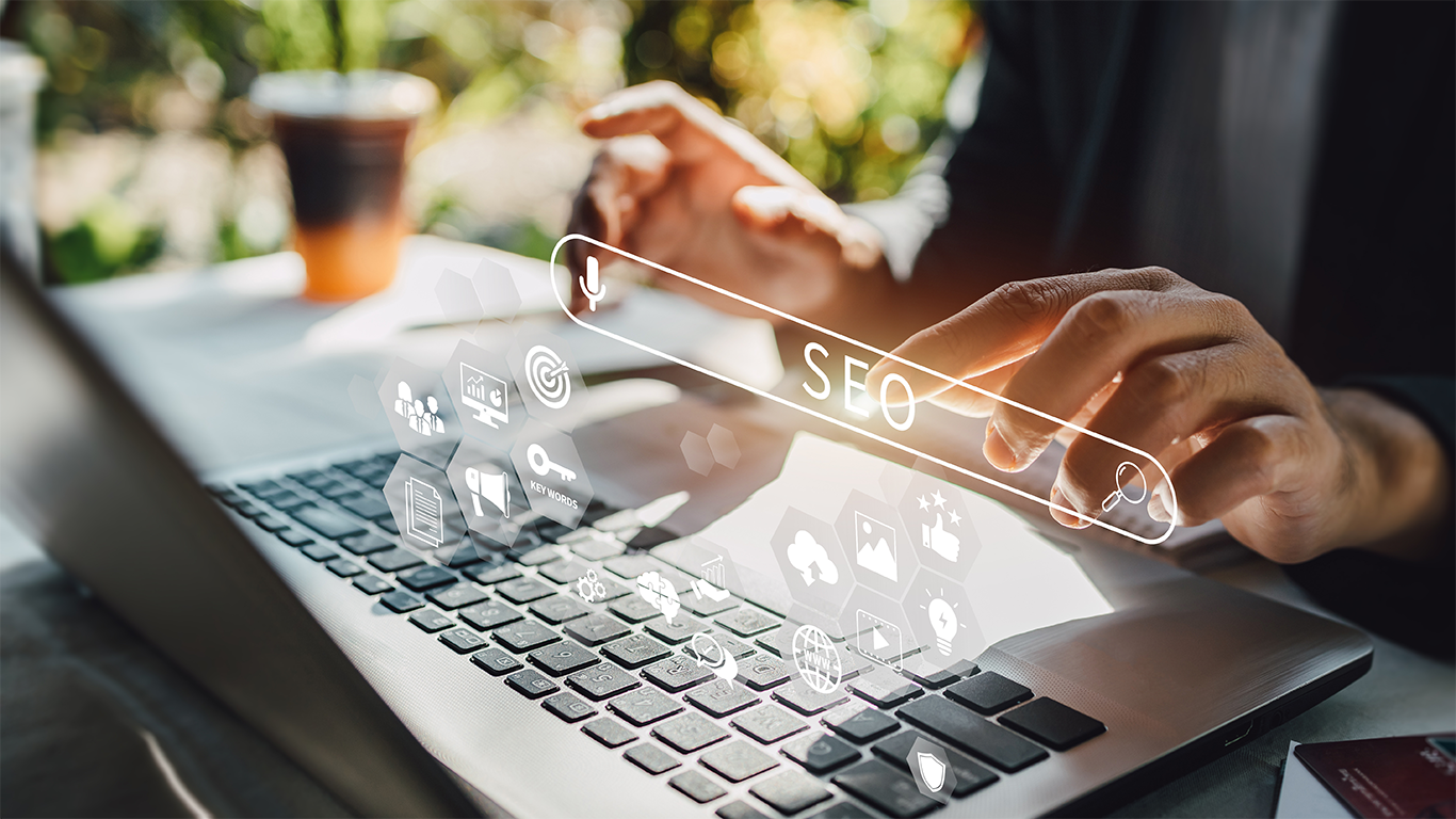 Person using a laptop with a digital SEO search bar and marketing icons displayed on screen.